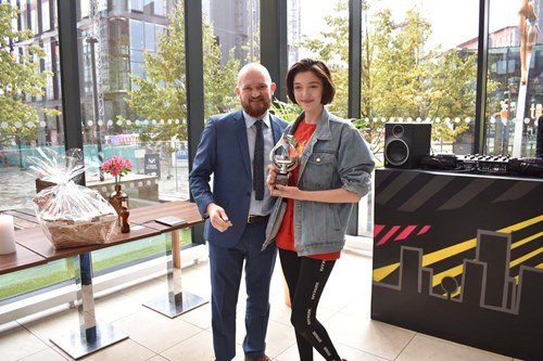 Winner poses holding a trophy with man in suit